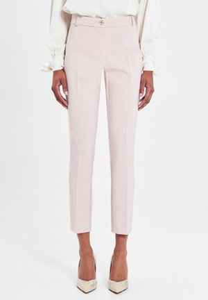 Pantalon en tissu rose doux avec une coupe ajustée, présentant une fermeture éclair et un bouton à l'avant, des détails de plis et une conception de jambe effilée.