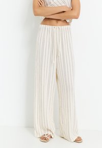 Pantaloni ampi leggeri di colore crema con righe verticali, vita con coulisse regolabile e tessuto morbido. Ideali per un look casual.
