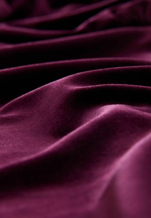 Deep burgundy fabric with soft, smooth texture, displaying gentle folds and waves, highlighting its luxurious appearance and rich color.