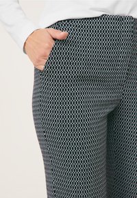 Pantaloni a motivi in bianco e nero con un disegno a diamante, dotati di una tasca laterale e di una texture morbida al tatto.