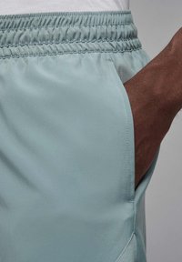 Lyseblå shorts med elastisk talje og sidelommer. Fremstillet af glat, syntetisk materiale med en let skinnende overflade.