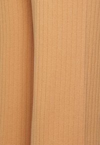 Tecido canelado e elástico na suave cor pêssego, apresentando riscas verticais e uma textura suave. Adequado para roupas que se ajustam ao corpo.