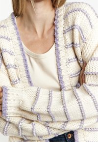 Cardigan en tricot épais couleur crème avec des accents violets. Comprend un col et des poignets côtelés, disposés en motif rayé. Texture confortable.