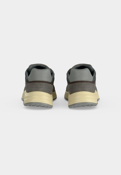 Paire de baskets grises et marron avec semelles écrues, vue de dos sur fond blanc.
