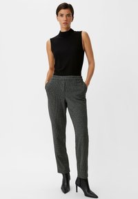 Black sleeveless turtleneck top paired with gray checkered trousers featuring an elastic waistband and slim fit, complemented by black ankle boots.