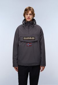 Grijze waterdichte jas met een hoge kraag, capuchon en elastische trekkoorden. Heeft een voorzak en een Norse vlag patch.