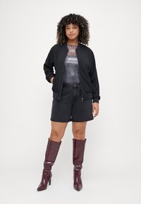 Black bomber jacket, metallic animal print top, black denim shorts, and glossy burgundy knee-high boots. Smooth textures and casual design.