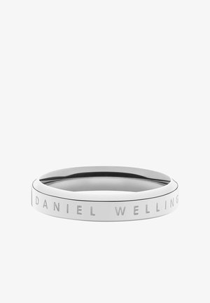 Bague en argent poli gravée de "DANIEL WELLINGTON" autour de la bande extérieure sur fond blanc.