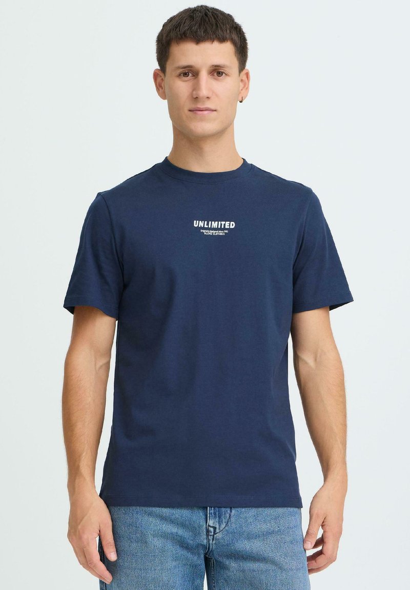 Laivastonsininen puuvillainen pyöreäkauluksinen t-paita, jossa on lyhyet hihat ja valkoinen "UNLIMITED"-kuvio rinnassa.
