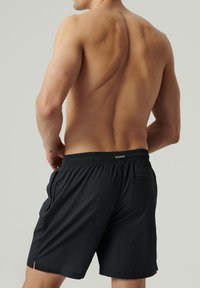 Czarne szorty kąpielowe z teksturowanej tkaniny, elastycznym pasem, bocznymi kieszeniami i małą kieszenią z tyłu. Zawierają rozporki po bokach.