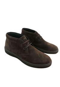 Stivaletti alla caviglia in suede marrone con punta arrotondata, cuciture minime e suole in gomma piatta. Presentano lacci e un design a scollo basso attorno alla caviglia.