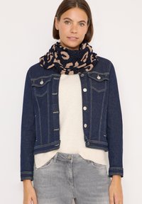 Damejakke i mørkeblå denim med sølvknapper, parret med en cremefarvet sweater og et marineblåt tørklæde med et beige leopardmønster.