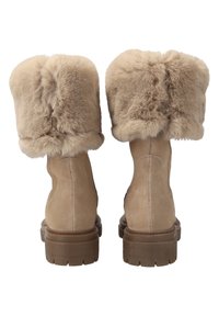 Bottines en suède beige avec un revers en fausse fourrure en haut, dotées d'une semelle en caoutchouc brun robuste et d'une texture lisse.