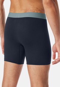 Marineblauwe boxershorts met een lichtgrijze tailleband, met een zachte textuur en een strakke pasvorm, ontworpen voor comfort en ondersteuning.