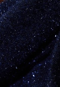 Tejido azul marino con una textura suave y aterciopelada, que presenta sutiles detalles brillantes creados por fibras reflectantes de luz en toda su superficie.