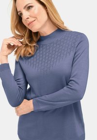 Pull en maille de couleur bleu doux avec des poignets côtelés, un col montant et un motif texturé sur le devant, comprenant un motif en losanges.