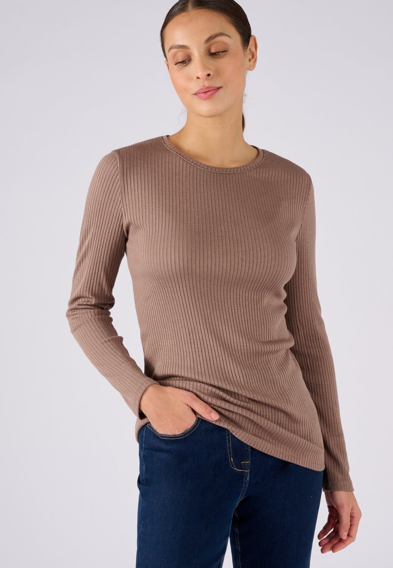 Maglietta a maniche lunghe marrone a costine con scollatura rotonda, design aderente e texture liscia abbinata a jeans in denim blu scuro.