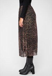 Leopardprint midi rok van lichtgewicht, doorschijnende stof met een zwarte elastische tailleband, gecombineerd met zwarte laarzen tot de knie met hakken.