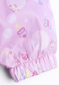 Tissu rose clair avec des motifs ludiques de glaces, de papillons et de formes géométriques, avec des poignets élastiqués et une texture douce.