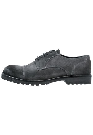 Chaussure derby homme en daim gris foncé à lacets, bout rapporté et semelle noire épaisse et robuste vue de profil.
