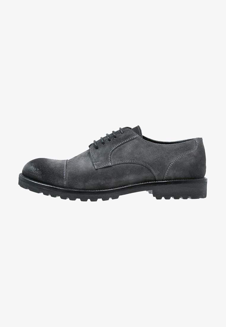 Chaussure derby homme en daim gris foncé à lacets, bout rapporté et semelle noire épaisse et robuste vue de profil.