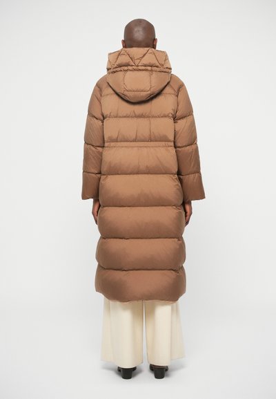 Brun pufjakke med hætte, der har et quiltet design og lange ærmer, som går til midt på læggene. Glat tekstur og afslappet pasform.