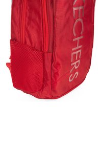 Mochila roja con un acabado texturizado, que cuenta con dos compartimentos con cremallera, un bolsillo de malla en el lateral y un logo impreso en gris.