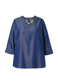 Blouse bleue à manches longues avec col en V, coutures décoratives au niveau du col et des poignets, et doublure intérieure du col à motif.