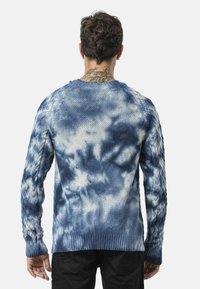 Blauwe tie-dye gebreide trui met een ribbelzoom en kabelgebreide mouwen, met een gestructureerd patroon en een getailleerde manchetten.