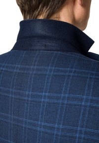 Granatowa kurtka w kratę z wysokim kołnierzem, z delikatnymi detalami haftu i gładką teksturą wełnianej mieszanki, podkreślającą jej dopasowany fason.