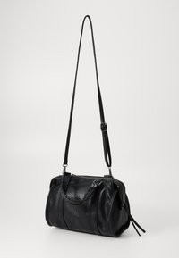 Sac à main noir en cuir texturé, avec fermeture éclair et une bandoulière tressée. Dispose d'une bandoulière longue détachable.