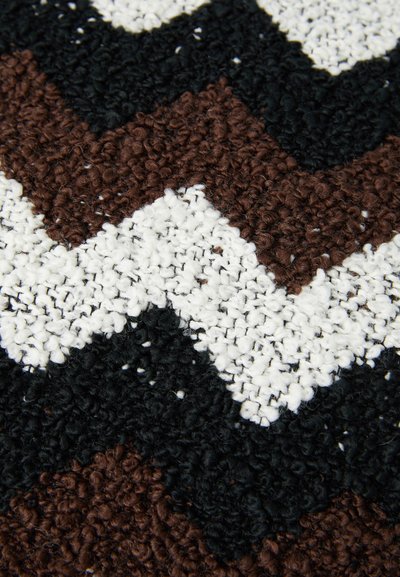 Brown, black, and white zigzag patterned rug with a textured surface, featuring a looped pile construction and soft fibers.