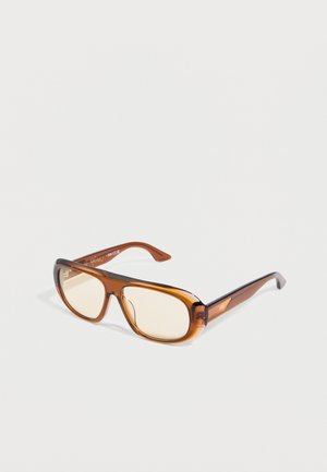 Lunettes de soleil rectangulaires translucides marron avec des verres légèrement teintés et une forme subtile en œil de chat sur un fond blanc.