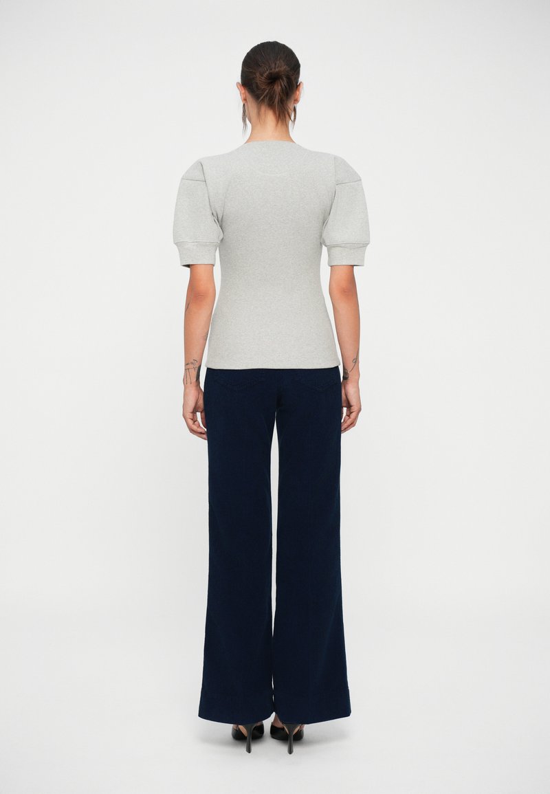 Gray fitted top with puffed short sleeves, paired with navy wide-leg pants. Material appears smooth, with a structured design.