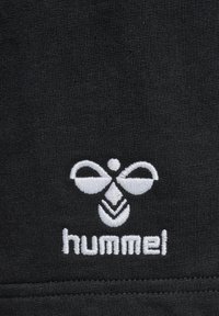 Black textile featuring a white embroidered logo of Hummel, with a symmetrical design resembling a stylized bee and text below.