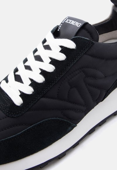 Baskets noires avec lacets blancs, panneaux en suède et nylon, marquage "ICEBERG" sur la languette, et détail de semelle texturée.