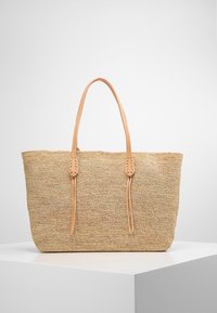 Borsa a rete beige con due manici in pelle color nocciola e dettagli di cucitura. Forma rettangolare spaziosa realizzata in materiale naturale testurizzato.