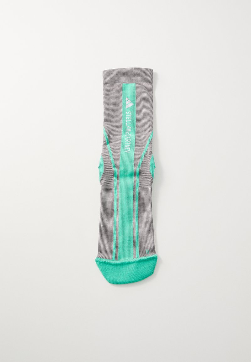 Calcetín deportivo gris con acentos en verde menta, que presenta una superficie texturizada y rayas verticales. Incluye un talón y puntera reforzados.