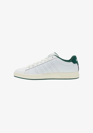 Baskets basses blanches avec des rayures perforées sur les côtés, doublure intérieure verte, languette de talon verte et semelle couleur crème.