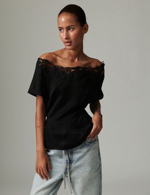 Zwart off-shoulder top met kanten rand bij de hals, met een losse pasvorm en korte mouwen, gecombineerd met lichtblauwe denim jeans.