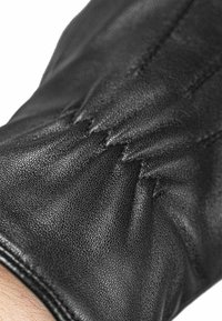 Schwarze Lederhandschuhe mit strukturiertem Finish, besitzen ein gefältetes Design und feine Nähte am Handgelenk. Glatte Gesamtoberfläche.