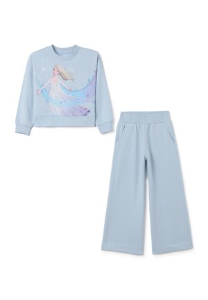 Hellblaues Sweatshirt mit Grafik eines Charakters, kombiniert mit passender weiter Hose. Glattes Material mit elastischem Bund und Taschen.