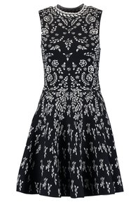 Svart ärmlös klänning med vita blommönster, rund halsringning, åtsittande kjol och utsvängd nederdel. Tillverkad av mjukt tyg.