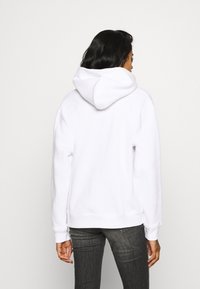 Biała bluza z kapturem, z długimi rękawami i ściągaczami na mankietach. Wykonana z miękkiego materiału, prezentowana na jednolitym tle.