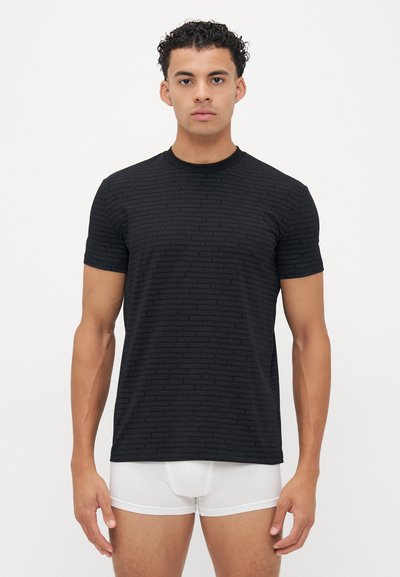 Sort kortærmet T-shirt med et struktureret mønster af gentagne mærkenavne. Rund halsudskæring, tætsiddende form, blødt stof. Båret med hvide trusser.