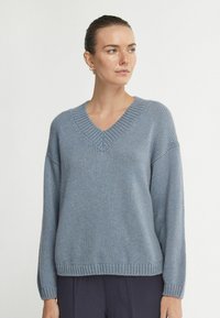 Jasnoniebieski sweter z dzianiny z dekoltem w serek, długim rękawem i prążkowanymi wykończeniami. Miękka tekstura i luźny krój, idealny do warstwowych stylizacji.