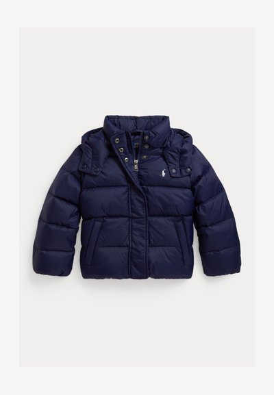 Tamno plavi puffer jakna s visokim ovratnikom, dugmadi na kopčanje, zatvaranjem na patentni zatvarač i bočnim džepovima. Napravljena je od sjajnoga, štitnog materijala.