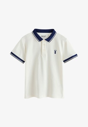 Biała koszulka polo z krótkim rękawem, granatowym kołnierzykiem i mankietami, trzema guzikami oraz małym granatowym logo jelenia na lewej piersi.