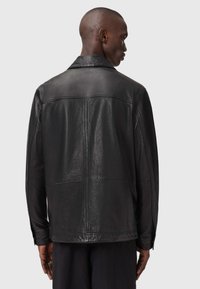 Jachetă din piele neagră cu o textură netedă, având un guler clasic și cusături vizibile. Spatele are un design minimalist, fără decorațiuni.