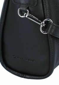 Bolso de piel negro con un acabado texturizado, que cuenta con herrajes plateados y un logo prominente. Correa ajustable y forma estructurada.